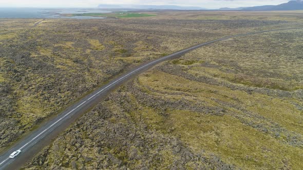 White Car on Road and Volcanic Lava Rock Formations. Iceland. Aerial View alt