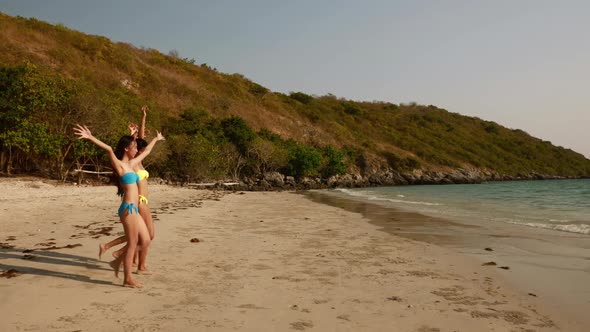 Group of women in bikini walking and having fun on the beach at sunset alt