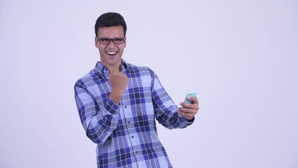 Happy Young Indian Hipster Man Using Phone and Getting Good News alt