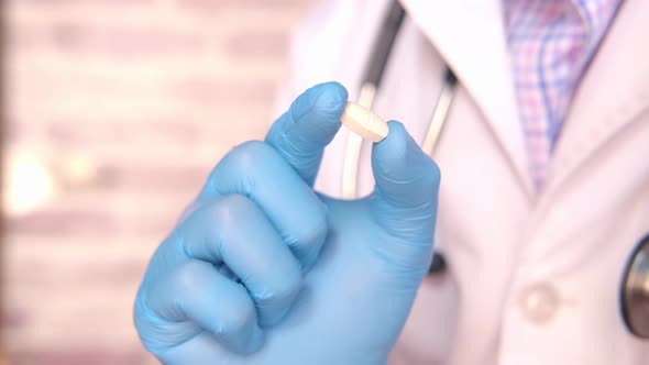 Doctor Hand in Latex Gloves Holding a Pill alt