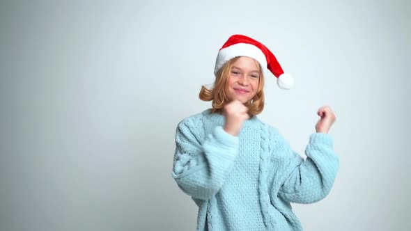 Happy Young Girl in Santa Claus Cap Dancing