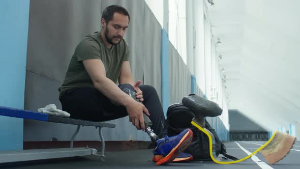 Athlete Putting on Prosthetic Leg before Workout alt
