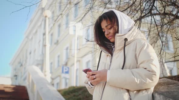 Attractive African American Teenage Girl Using Mobile Phone During Walk on Streets of Urban alt