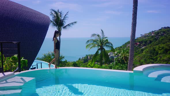 Sexy Woman In Swimming Suit In Luxurious Villa Walking to Sea View Infinity Pool