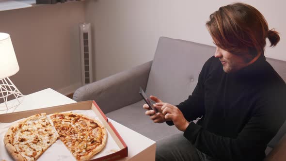 Young Caucasian Man Taking a Photo of Pizza on His Smartphone alt