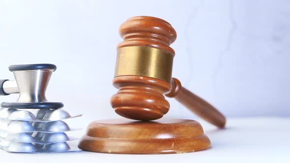 Close Up of Gavel, Stethoscope and Pills on Table  alt