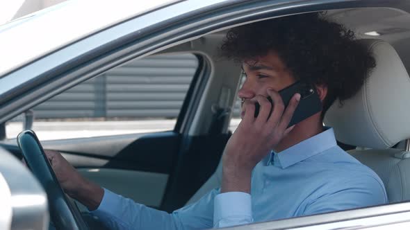 Attractive African American Young Businessman Speak By Phone in a Car Smile Sits Behind the Wheel alt
