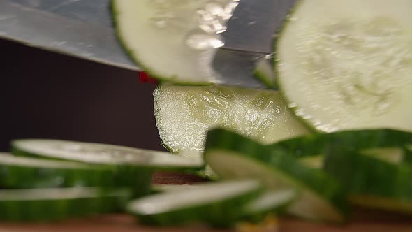 Woman Cuts a Green Cucumber with a Knife, Close-up