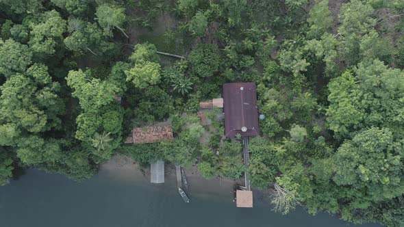 A house and boat at river margin in the amazon rainforest aerial shot alt