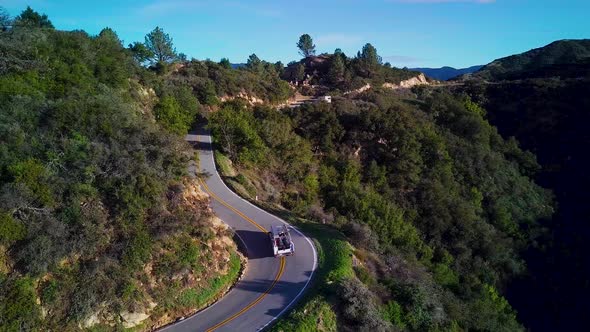 White Truck drives on Curvy Road in California Mountains, Drone Orbit alt