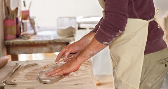Male potter working on clay in pottery workshop alt