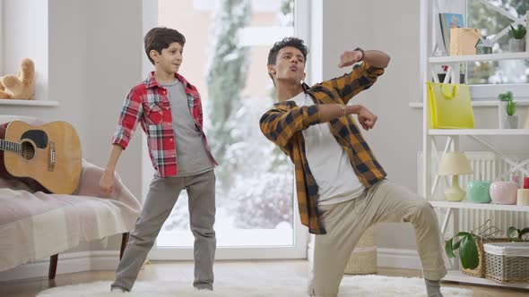 Joyful Middle Eastern Brothers Having Fun Dancing and Grimacing on Weekends at Home alt