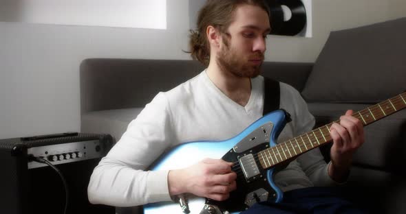 Young Man Plays the Electric Guitar at Home