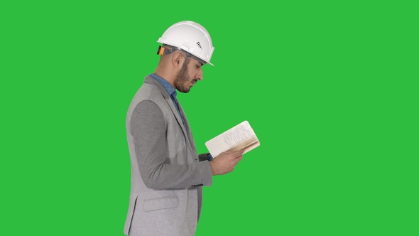 Young architect reading textbook or notebook while walking alt