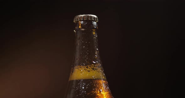 Bottle of Cold Beer on a Black Background. It Slowly Rotates. Condensate alt