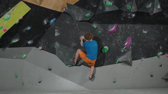 Young Climber Training on a Climbing Wall Practicing Rockclimbing and Moving Up  Slow Motion alt