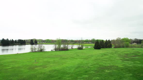 Aerial Drone Shot Flying Over Disc Golf Course Towards a Lake and Highway That is in the Distance in alt