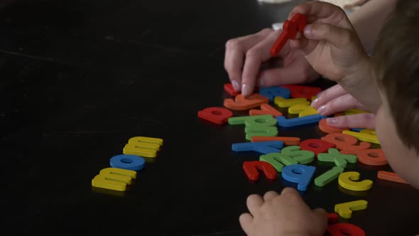 Mom teaches her son how to say the words on the cards at home at the table alt