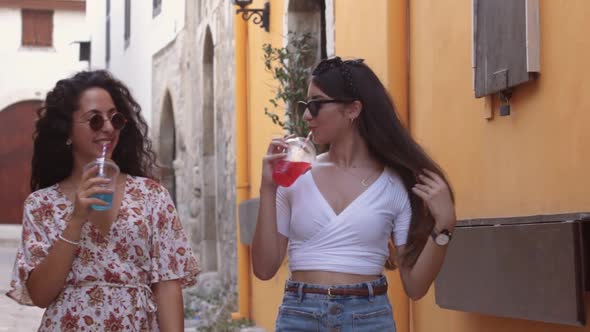 Tourist Women Walking Down Old City Street with Slush Drinks