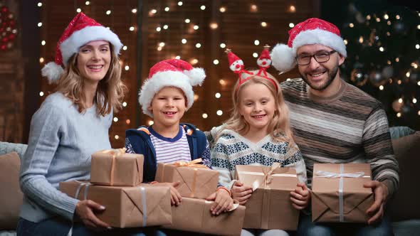 Family Wearing Christmas Horns and Santa Claus Hats Posing Together alt