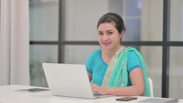 Indian Woman Showing Thumbs Up Sign While Using Laptop in Office alt