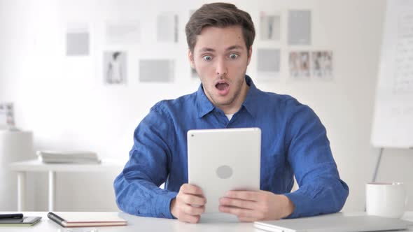 Casual Adult Man in Shock while Using Tablet alt