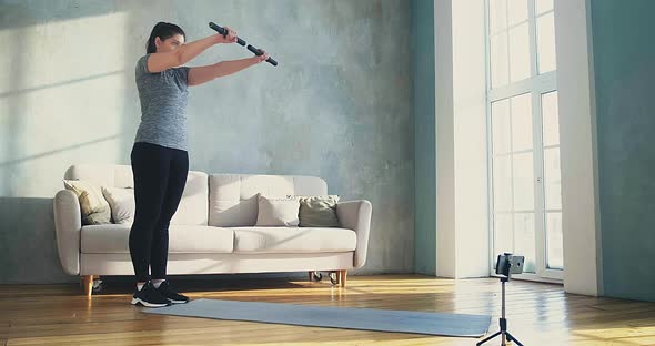 Woman Does Sports Exercises with Dumbbell Bars in Room alt