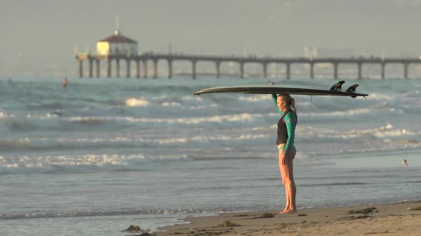 Portrait of woman stand-up paddleboard surfing at Manhattan Beach, CA pier in the background alt