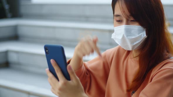 Young Asian woman wears protective medical face mask self-isolation making video chat, video call