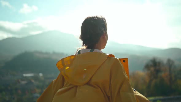 Joyful Freedom Girl in Yellow Jacket Standing with Open Arms Around Mountains and Hills Sun Lights alt
