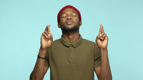 Slow Motion of Hopeful African American Man Pleading Praying to God with Crossed Fingers and Closed