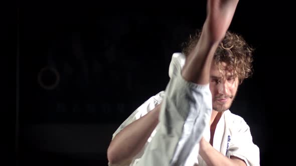 Young Martial Arts Athlete in Kimono, Practicing Karate Kick. Black Background alt