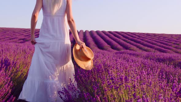 Young Woman in White Dress Walking Through a Lavender Field on Sunset