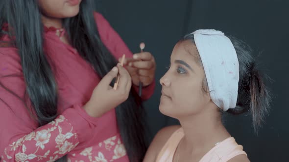 Make-up artist work in progress by highlighting of the lower lash line with a brown pencil and brush alt