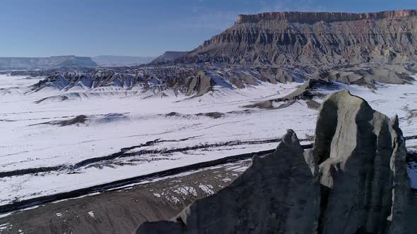 Flying backwards over desert rock formation in winter alt