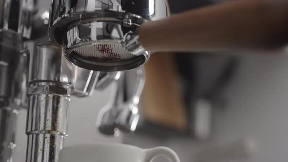 Slow Motion Low Angle Shot of Coffee Extraction with Naked Portafilter Into White Cup alt