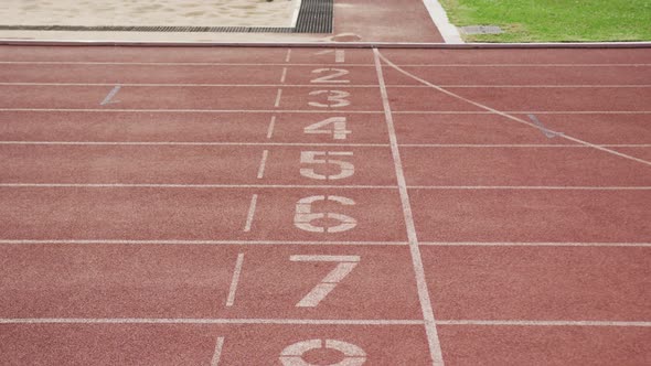 Disabled mixed race man with prosthetic legs running through a finishing line on race track alt