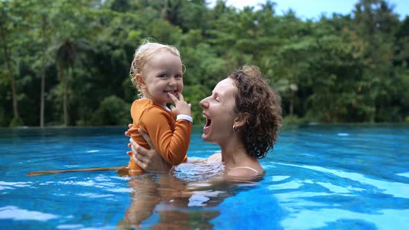 Mom and Baby in the Pool are Happy Together Laughing with Pleasure alt