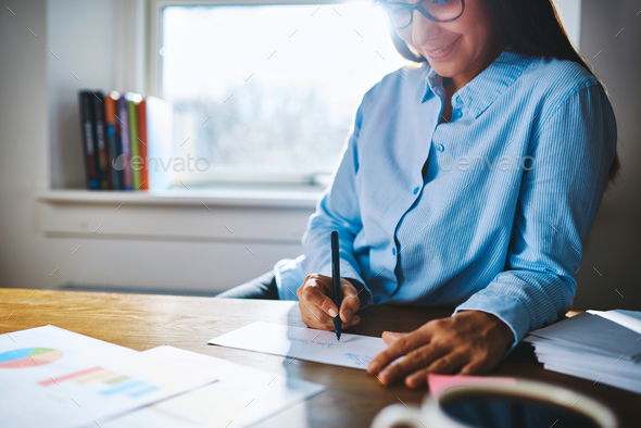 Cheerful woman writing at desk - Stock Photo - Images