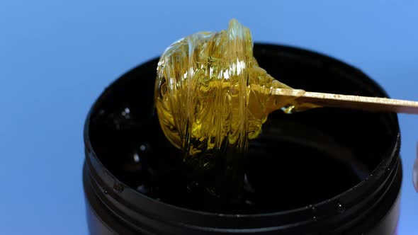 Sugar paste or honey wax for hair removal, dripping from wooden wax sticks - depilation and beauty. alt