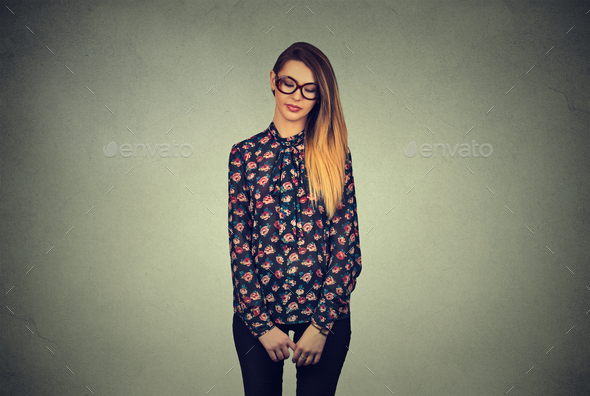 Sad shy insecure young woman in glasses looking down avoiding eye contact