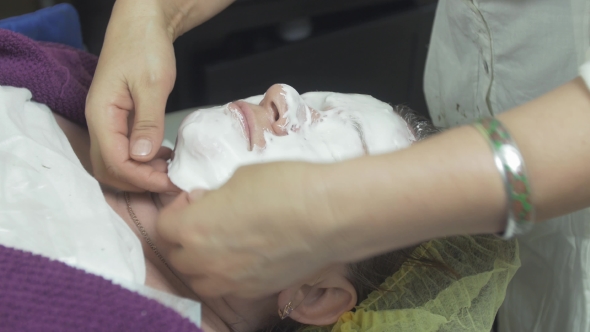 Cosmetologist Put Off Algae Mask On Face Of Fat Woman In Beauty Saloon By Spoon alt