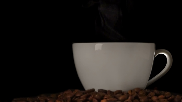 Cup Of Steaming Coffee And Coffee Beans Over Dark Background