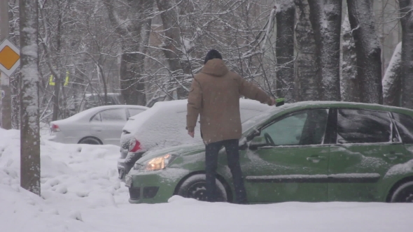 Man Cleans a Car From The Snow alt