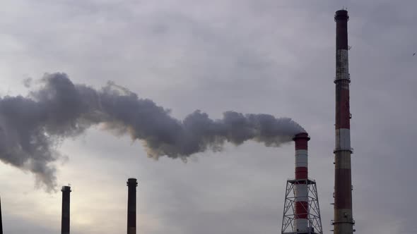 Industrial Chimney with Large Quantity of Dark Smoke coming out. Dramatic Grey Clouds.