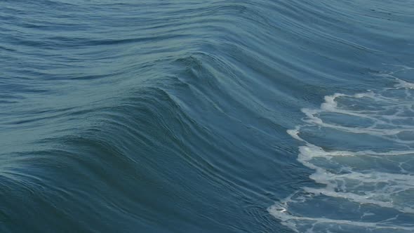 A powerful wave crashes at the beach and turns into whitewash. alt