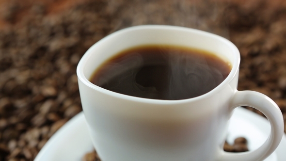 Pouring Coffee In Cup Surrounded By Coffee Beans