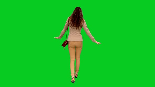 Back View of Young Woman Stumbling During Walking on Green Screen
