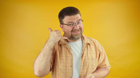 Adult male showing call me gesture, pointing finger on camera, communication alt