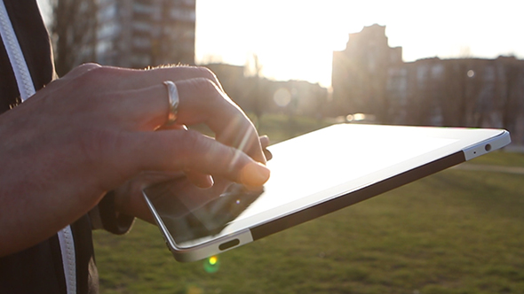 Man Working on a Tablet on The Sunset Background alt